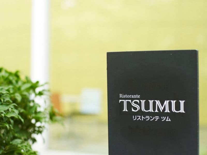 緑に映える「Ristorante TSUMU」の店舗看板。落ち着いたデザインの看板がゲストを上質な食の世界へと誘います。