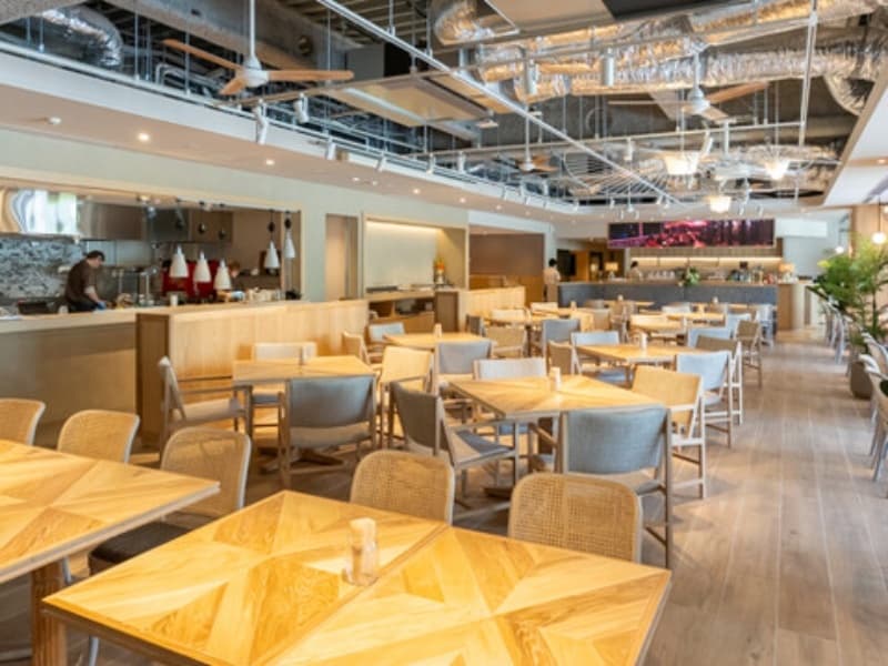 木目テーブル・ラタンチェアが並ぶナチュラルリゾートな店内。天井も高く、広々しているので、大人数のご宴会でも圧迫感を感じることなくお過ごしいただけます。