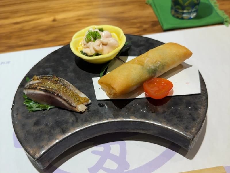 旬の食材を活かした彩り豊かな前菜盛り合わせ。春巻きなどの3種の肴、店主の丁寧な仕事が光る一皿が食欲をそそります。