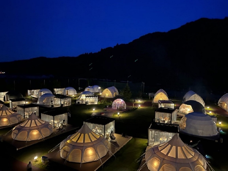  夜空の下、幻想的な光に包まれたテントが並ぶ夜の施設
