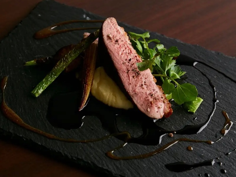 フランス産の上質な鴨胸肉を絶妙な火入れ加減でローストし、外は香ばしく、中はしっとりジューシーに仕上げた「鴨胸肉のロースト」。断面のロゼ色も食欲をそそる贅沢な逸品です。赤ワインとオレンジの2種のソースが織りなす、立体感のあるおいしさをお楽しみください