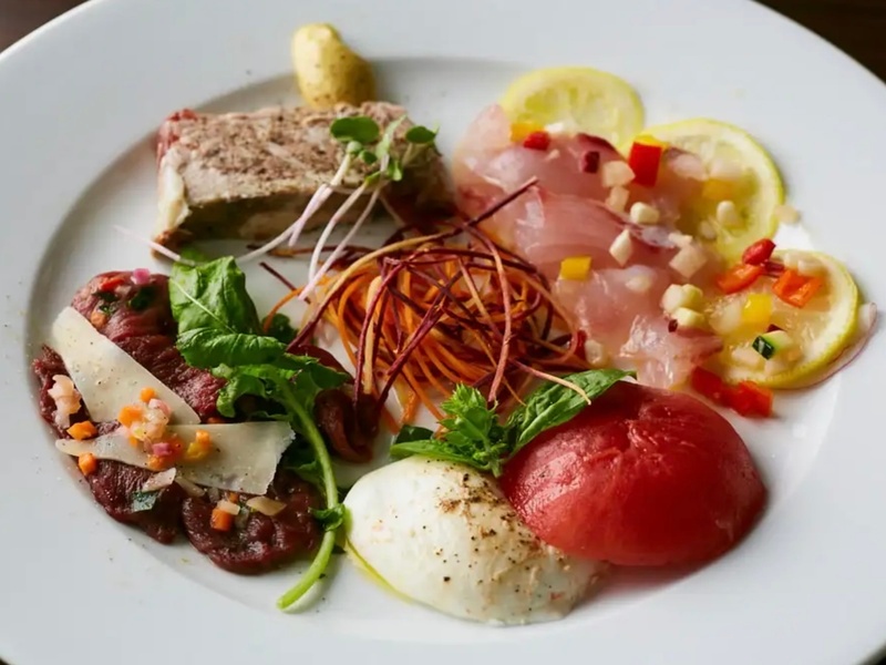 「お料理のみコース」内「前菜盛り合わせ」の「鮮魚のカルパッチョ」「イタリア産水牛モッツァレラのカプレーゼ」など、素材の味をいかした、見て美しい食べておいしいアラカルトが並びます。何がでてくるかはお店に行ってからのお楽しみ！