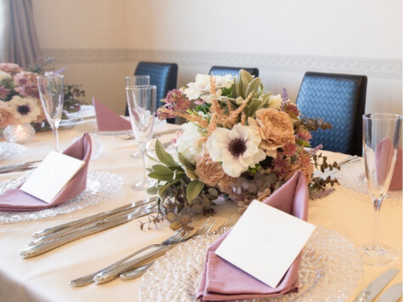 ピンクのナプキンと花のアレンジメントが彩る、上品なテーブルコーディネート。大切なゲストをお迎えする心遣いが感じられます。